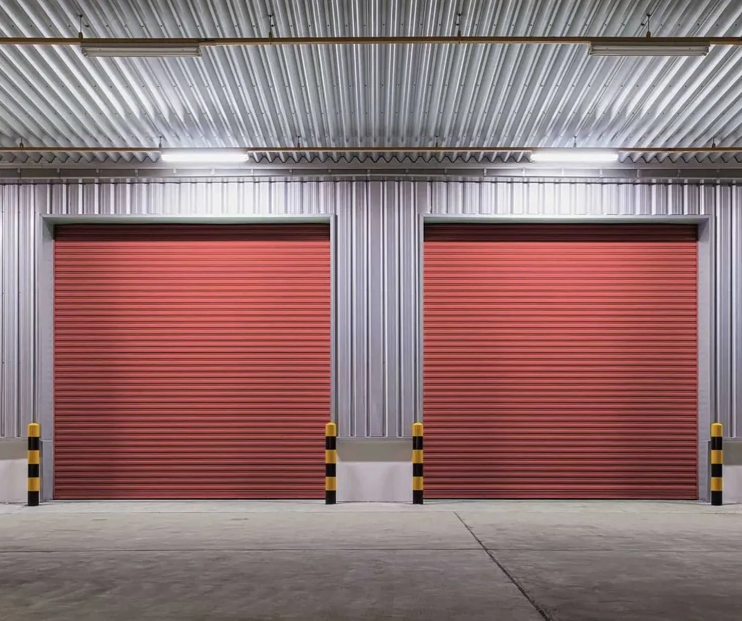 Pair of red galvanized roller shutters inside a steel-framed warehouse